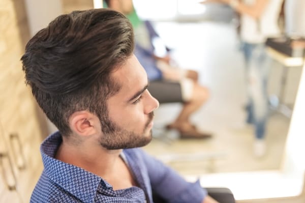 side view of a seated young casual man with nice hairstyle, waiting