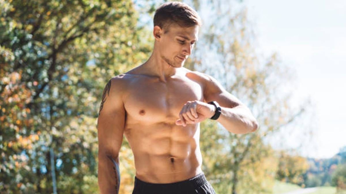 Young athlete checking out time while working out in the nature shirtless